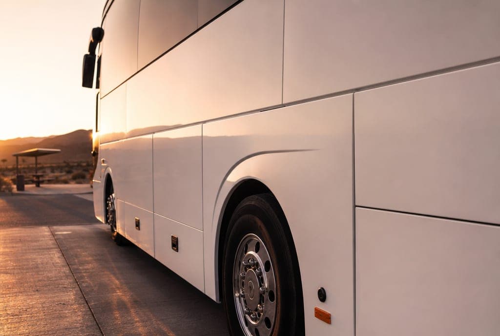 The side of a white coach at a quiet desert rest stop at dawn